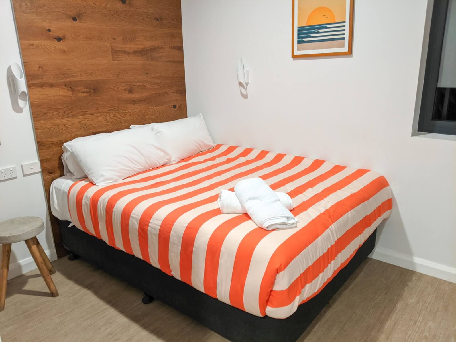 a bed with orange and white stripped bedding 