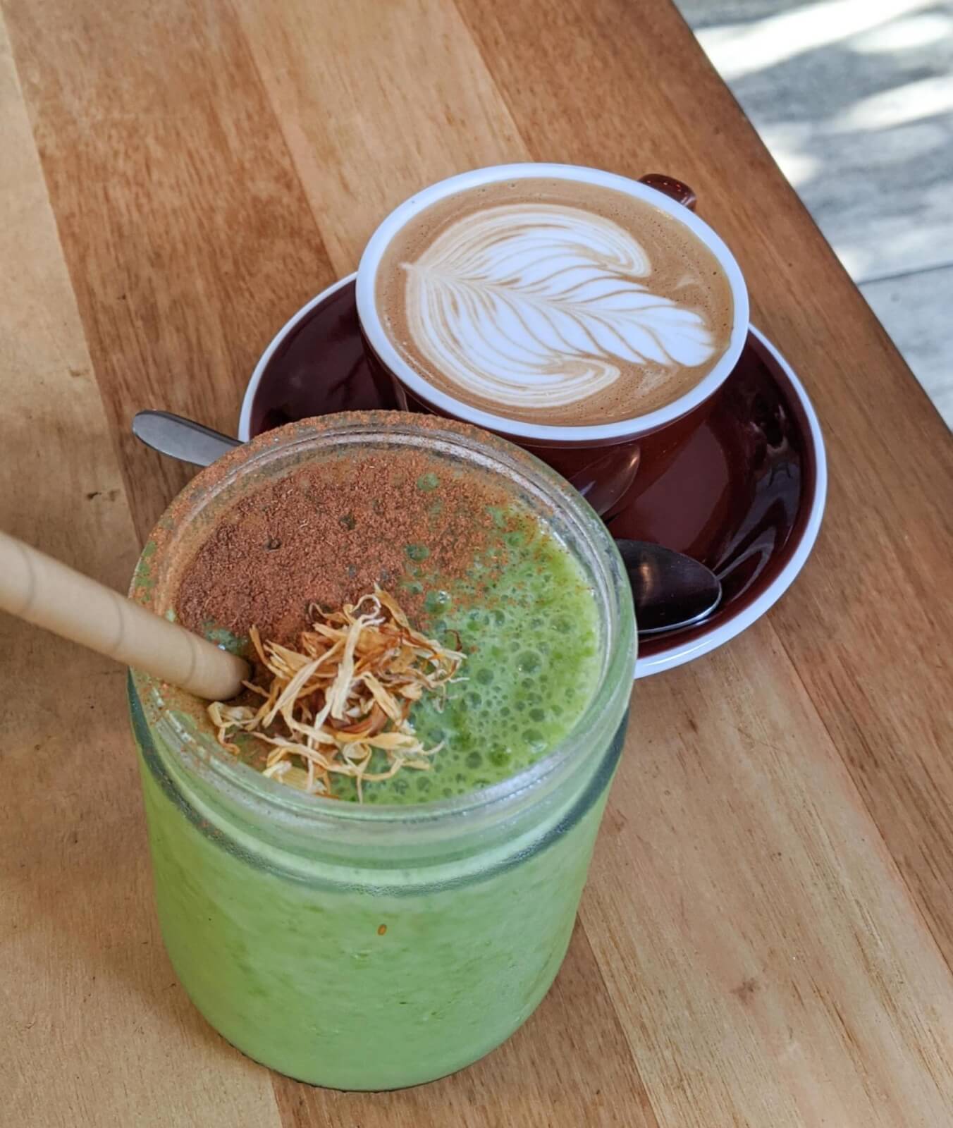 A green smoothie topped with cacao and a flat white coffee