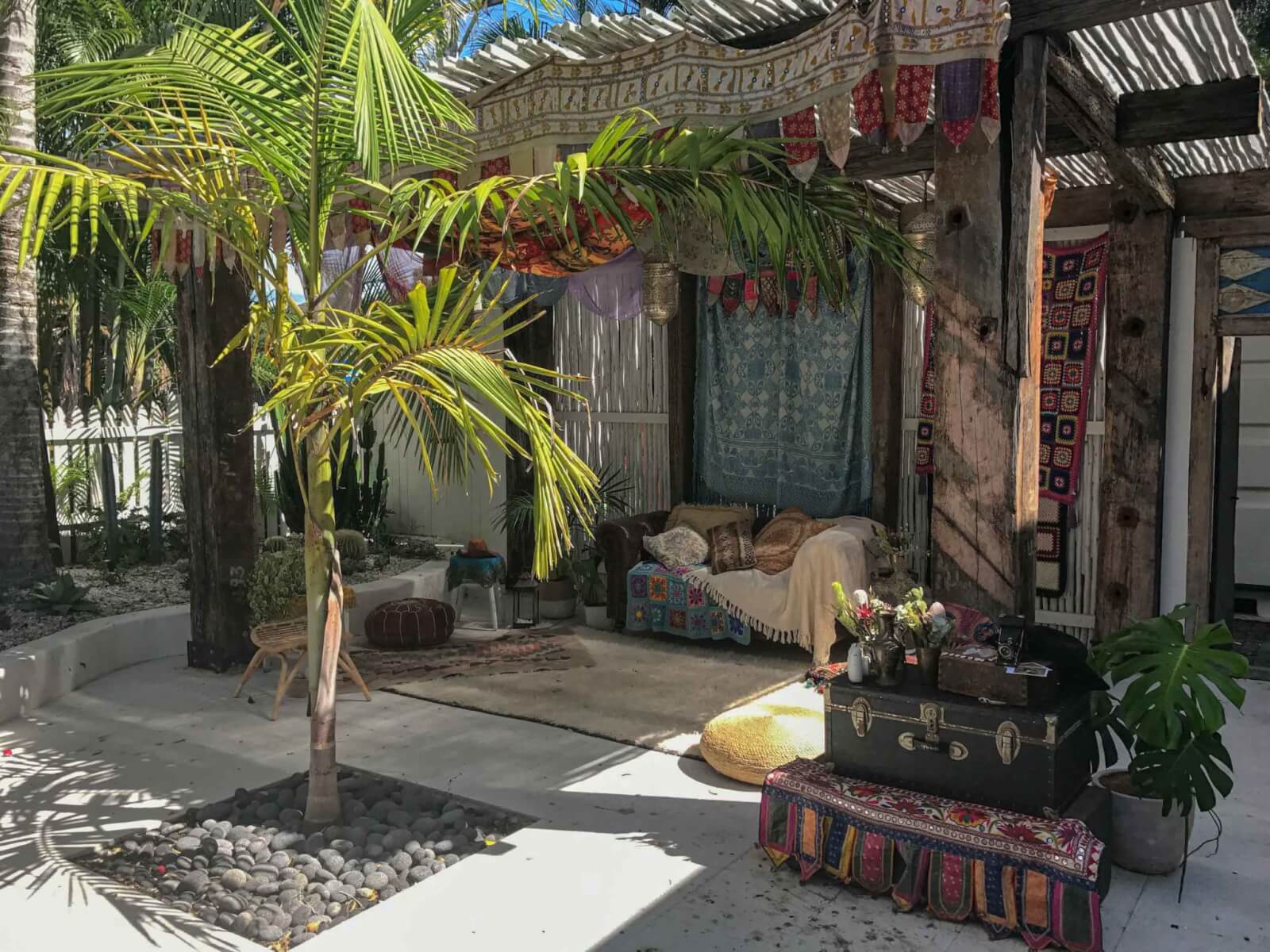 A courtyard filled with colourful fabrics, palms and trunks 