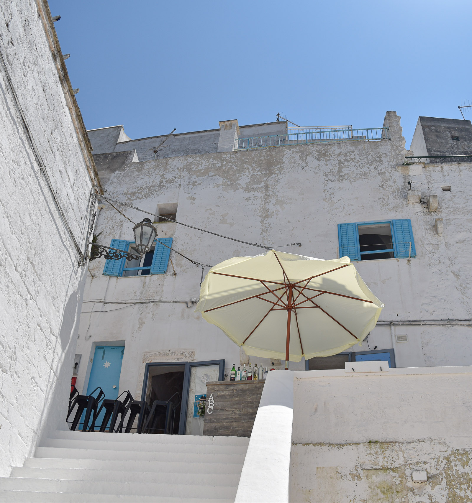 An al fresco bar with white walls and blue shutters in Ostuni